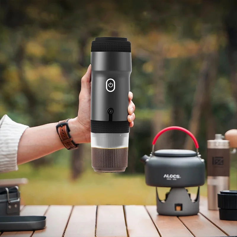 webp, doğada, kamp malzemelerinin arasında, masa üzerinde , bir el espresso makinesini tutuyor.